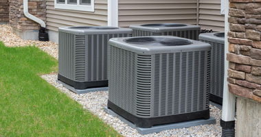 Cooling Service Residential air conditioners sitting on rock bed in backyard.