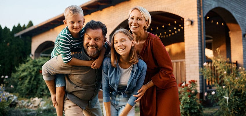 Happy family smiling at the camera, while enjoying the backyard.